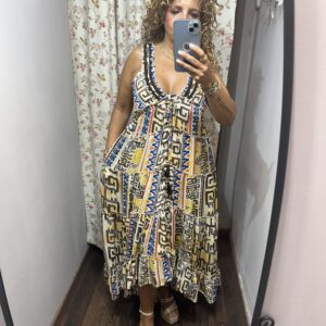 Vestido largo boho con estampado étnico en tonos tierra, azul y mostaza, escote en pico con lazada y corte amplio, ideal para un look cómodo y elegante de verano.
