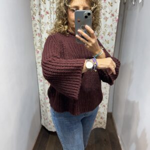 Jersey de punto color berenjena con mangas anchas y cuello redondo combinado con vaqueros.