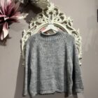 Jersey de mujer de punto grueso color gris claro con cuello vuelto y mangas largas.