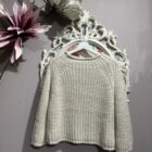 Jersey de punto color beiege con mangas anchas y cuello redondo combinado con vaqueros.