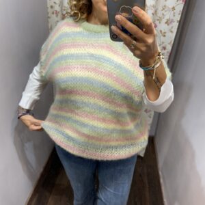 Chaleco de punto de rayas multicolor en tonos pastel rosa, verde y azul combinado con camisa blanca y vaqueros.