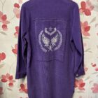 Espalda de sobrecamisa morada de mujer con bordado de alas y estrellas plateadas con lentejuelas.