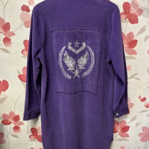 Espalda de sobrecamisa morada de mujer con bordado de alas y estrellas plateadas con lentejuelas.
