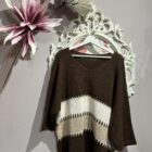 Jersey oversize marrón chocolate con rayas en tonos crudo y beige, escote en pico y manga amplia.