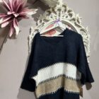 Jersey oversize marrón chocolate con rayas en tonos crudo y beige, escote en pico y manga amplia.